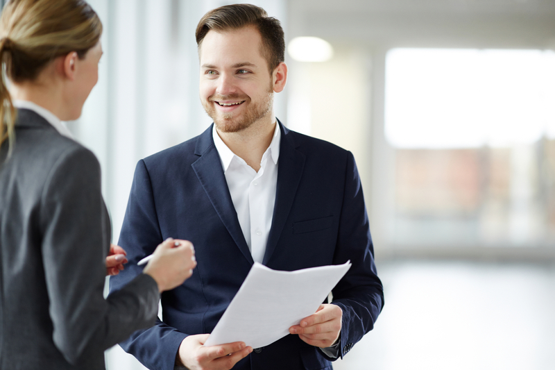 New Managers Inspired Leadership Coaching - Young man in elegant suit and his colleague discussing paper or terms of contract